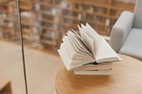 Open book on coffee table at library with blurred bookshelves as background Stock Photos