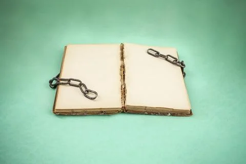 Open book with empty yellowed pages and broken chains in green vignetted ba.. Stock Photos