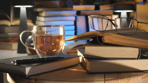 Open book with eyeglasses and tea cup on wooden table indoors Stock Footage 334774559