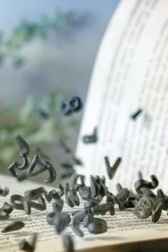 Open Book with Falling Black Letters  Knowledge and Education Concept Stock Photos