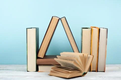 Open book, hardback colorful books on wooden table, blue background. Back to  Stock Photos