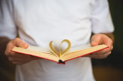 Open book with heart-shape sheets in the male hands Stock Photos