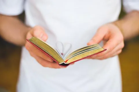 Open book with heart-shape sheets in the male hands Stock Photos
