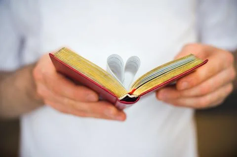 Open book with heart-shape sheets in the male hands Stock Photos
