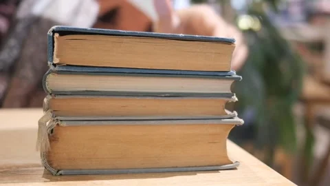 An open book with its pages gently turning rests on a wooden table in the breeze Stock Footage 296359074