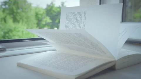 An open book lies on the windowsill of an open window, the rays of the sun on Stock Footage 159798462