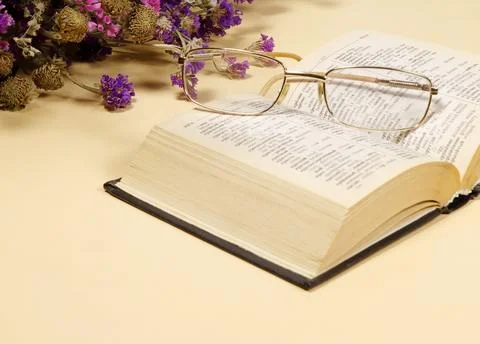 An open book on a light-colored table decorated with flowers. Stock-Fotos