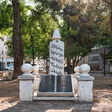 Open book monument with script on pedestal, surrounded by trees, in front of Stock Photos
