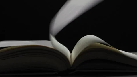 Open book pages turning slowly in the wind against a black background. Stock Footage 329921849