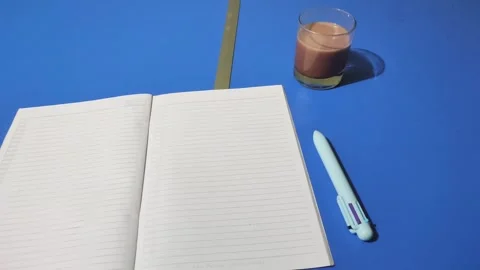 An open book with a pen beside it and a glass of chocolate milk Stock-Footage 325145019