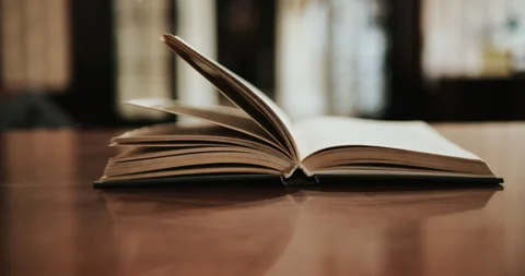 An open book placed on the table, by the wind blowing until the page flipped  Stock Footage 147276763
