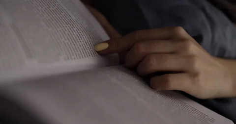 An open book, read and the lines followed by a woman's finger. Slow motion. Stock Footage 145603357