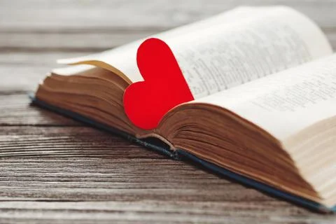 Open book with red heart shaped paper bookmark on wooden background Stock-Fotos