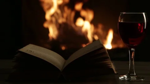 Open book with red wine in front of the fireplace. Stock Footage 72686735