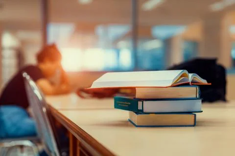 Open book on stack of books in library at school, university, college. Stock Photos