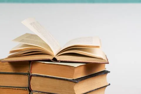 Open book, stack of hardback books on table Foto stock