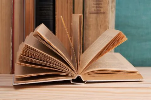 Open book, stack of hardback books on wooden table Stock Photos
