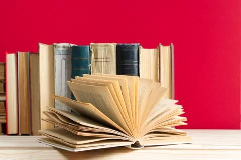 Open book, stack of hardback books on wooden table Stock Photos