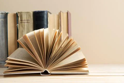 Open book, stack of hardback books on wooden table Stock Photos
