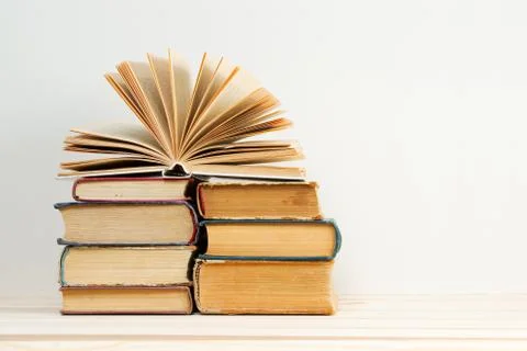 Open book, stack of hardback books on wooden table Stock Photos