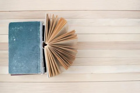 Open book, stack of hardback books on wooden table Stock Photos