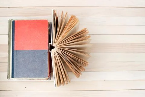 Open book, stack of hardback books on wooden table Stock Photos