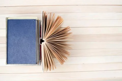 Open book, stack of hardback books on wooden table Stock Photos