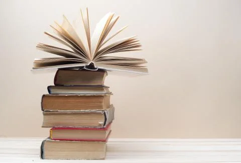 Open book, stack of hardback books on wooden table Stock Photos