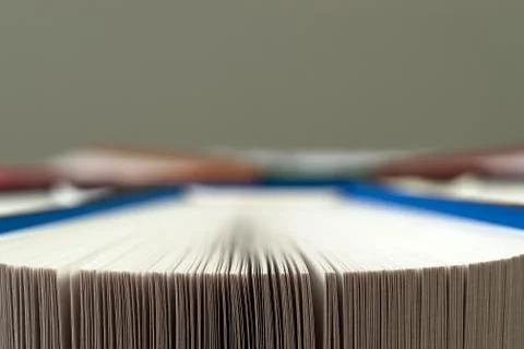 Open book, stack of hardback books on wooden table. Stock Photos
