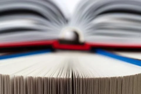 Open book, stack of hardback books on wooden table. Stock Photos