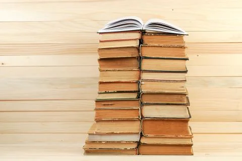 Open book, stack of hardback books on wooden table Stock Photos