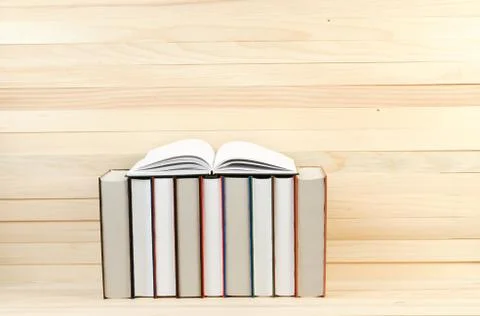 Open book, stack of hardback books on wooden table Stock Photos