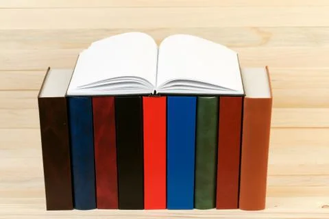 Open book, stack of hardback books on wooden table Stock Photos