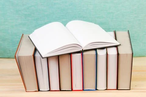 Open book, stack of hardback books on wooden table Stock Photos