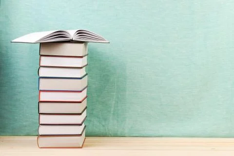 Open book, stack of hardback books on wooden table Stock Photos