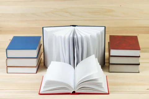 Open book, stack of hardback books on wooden table Stock Photos