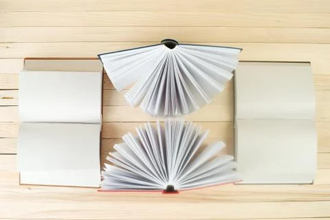 Open book, stack of hardback books on wooden table Stock Photos