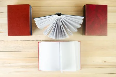 Open book, stack of hardback books on wooden table Stock Photos