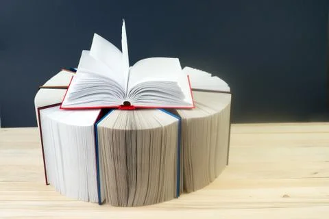 Open book, stack of hardback books on wooden table Stock Photos