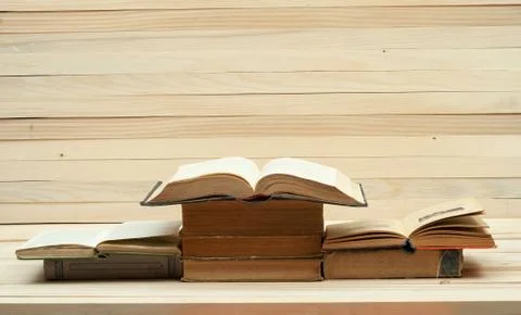 Open book, stack of hardback books on wooden table Stock Photos
