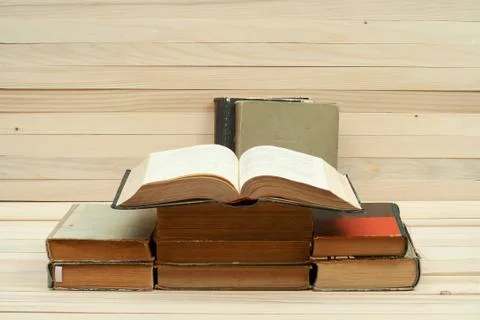 Open book, stack of hardback books on wooden table Stock Photos