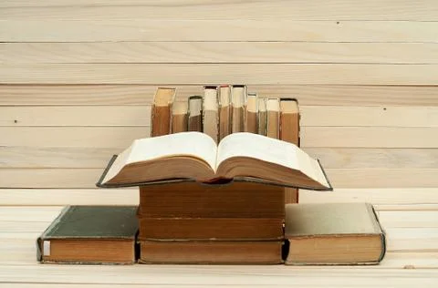 Open book, stack of hardback books on wooden table Stock Photos