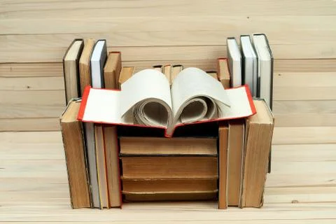 Open book, stack of hardback books on wooden table Stock Photos