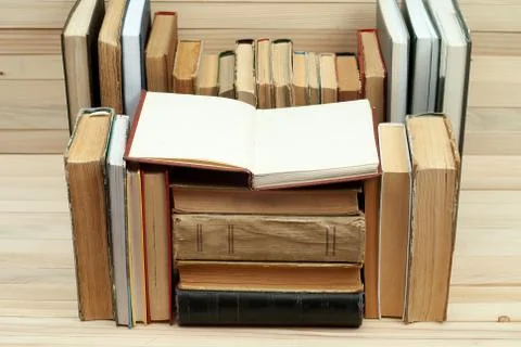 Open book, stack of hardback books on wooden table Foto stock