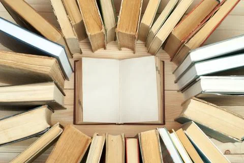Open book, stack of hardback books on wooden table Stock Photos