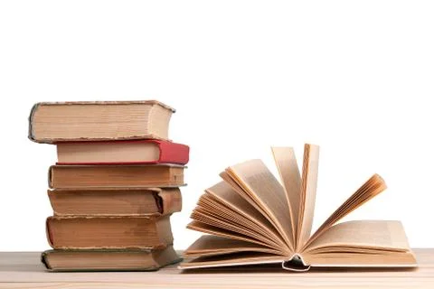 Open book, stack of hardback books isolated on wooden table. Back to school.. Stock Photos