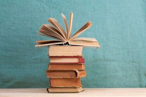 Open book, stack of hardback books on wooden table Stock Photos