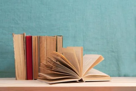 Open book, stack of hardback books on wooden table Stock Photos