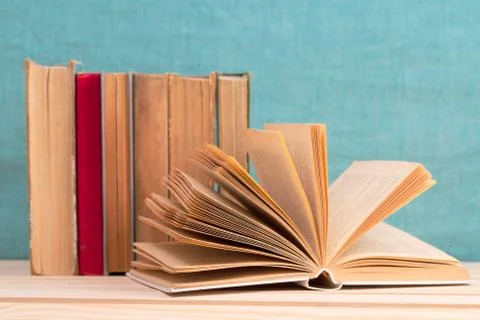 Open book, stack of hardback books on table. Foto stock