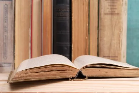 Open book, stack of hardback books on wooden table Foto stock